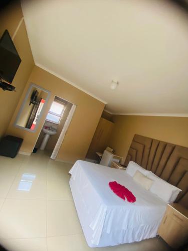 a bedroom with a white bed with a red shirt on it at Sky city luxury guest house in Alberton