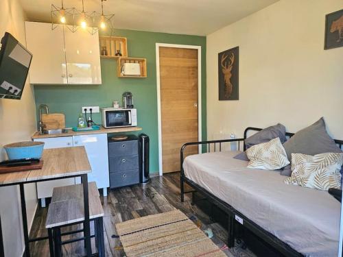 Cette chambre comprend un lit, une table et une cuisine. dans l'établissement Joli Studio indépendant à 20 min de Paris, à Villennes-sur-Seine
