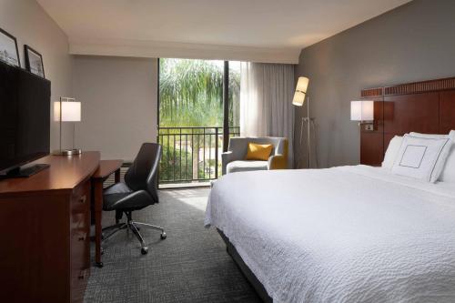 a hotel room with a bed and a desk and a television at Courtyard by Marriott Bradenton Sarasota/Riverfront in Bradenton
