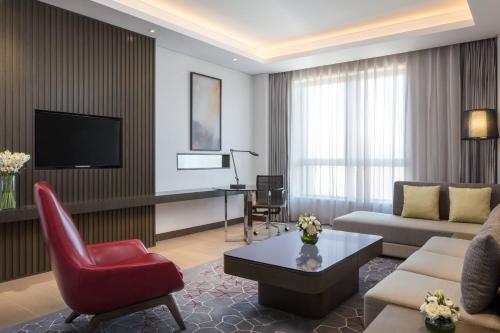 a living room with a couch and a red chair at Courtyard by Marriott Tianjin Hongqiao in Tianjin