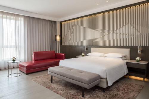 a bedroom with a large bed and a red chair at Courtyard by Marriott Tianjin Hongqiao in Tianjin
