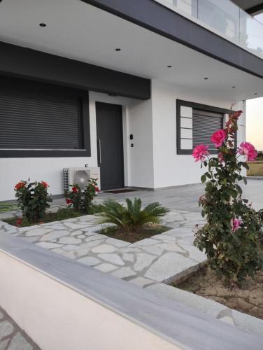 a white house with pink flowers and a walkway at Luxury Apartments in Kostakioí