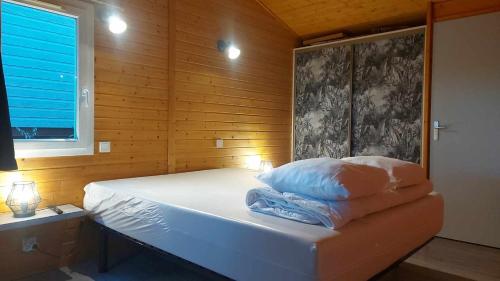 - une chambre avec un lit blanc et un mur en bois dans l'établissement Cape Agde Charmant chalet sur le Mont Saint Loup, à Agde