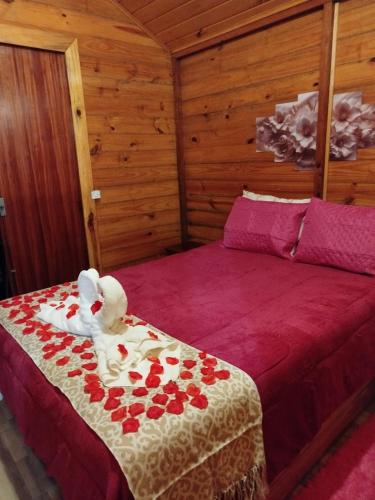 a bedroom with a bed with red roses on it at Cabanas La Suisse in Campos do Jordão