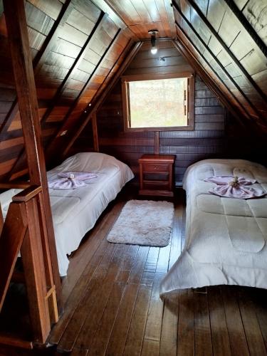 a attic room with two beds and a window at Cabanas La Suisse in Campos do Jordão