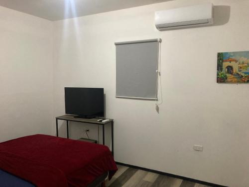 a room with a bed and a television on a table at Departamento amplio y tranquilo in Mexicali