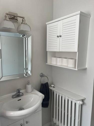 a white bathroom with a sink and a mirror at Entire Apartment in Kingston