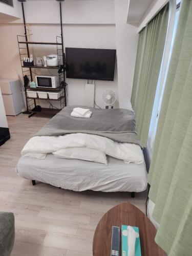 a bedroom with a bed with a tv and a table at JR Shin-Osaka 30s, Direct to Kansai Airport 關西空港直達,Shinkansen to Tokyo, Tokyo & Nagoya, Universal Studio 16 mins, Umeda 6 mins, Kyoto 25 mins, Early Check-In in Osaka