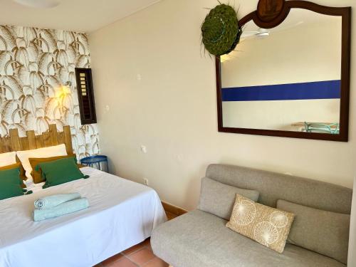 une chambre avec un lit, une chaise et un miroir dans l'établissement L'escale bleue, à La Trinité