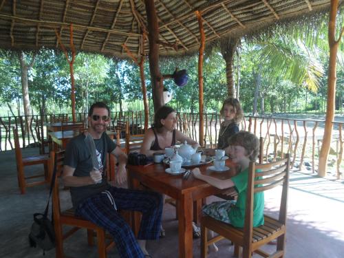 a group of people sitting around a wooden table at Sunshadow Chalet in Tangalle