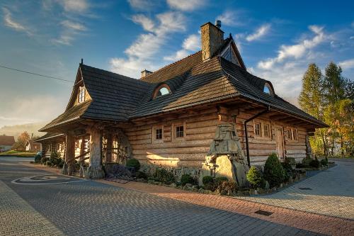 a wooden house with a roof on a street at Noclegi Styrnol & SPA in Zawoja