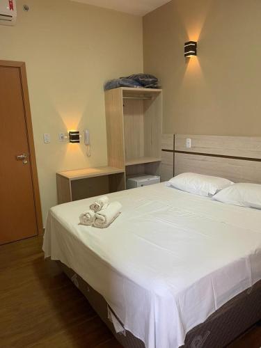 a bedroom with a large white bed with towels on it at Hotel Maria da Fé in Aparecida