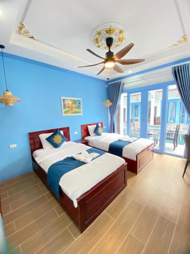 a bedroom with two beds and a ceiling fan at Sadakham Royal View Hotel in Luang Prabang