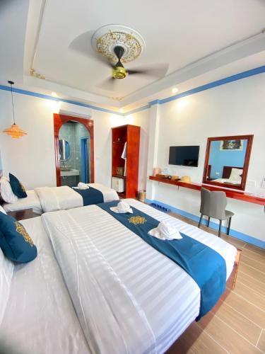 a bedroom with two large beds and a television at Sadakham Royal View Hotel in Luang Prabang