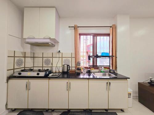 a kitchen with white cabinets and a sink and a window at Entire 1 Bedroom Apartment in Suva City Centre in Suva