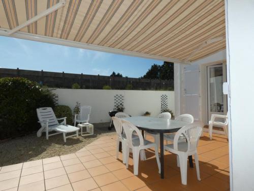 d'une terrasse avec une table et des chaises blanches. dans l'établissement Maison familiale 94m² à 1,2km des plages - Jardin clos, 3 chambres, terrasse équipée - FR-1-540-255, à Notre-Dame-de-Monts