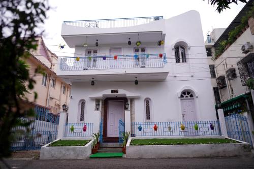 a white house with a balcony on top of it at The Nerd Nest Kolkata in Kolkata