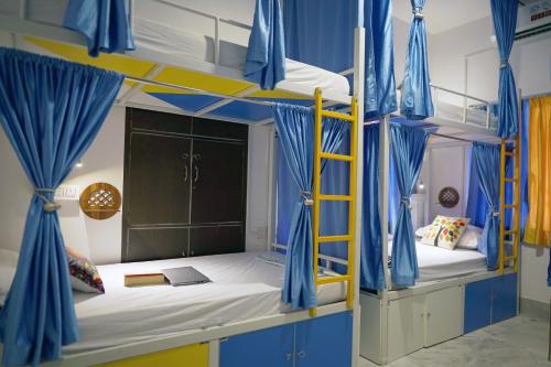 a bedroom with two bunk beds with blue drapes at The Nerd Nest Kolkata in Kolkata