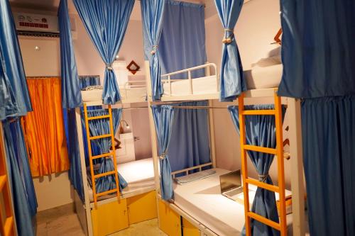 a room with four bunk beds and blue curtains at The Nerd Nest Kolkata in Kolkata