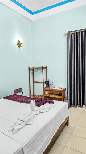 a bedroom with a bed and a table and a window at Vi Hotel in Vũ Lâm