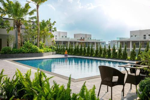 a swimming pool with two chairs and a table and some buildings at Armin Homes Studio at Solforest Ecopark in HÆ°ng YÃªn