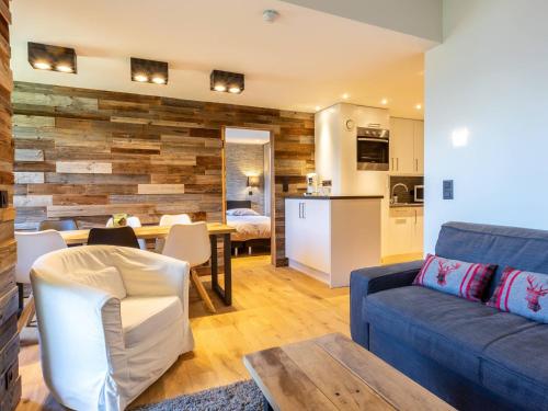 un salon avec un canapé bleu et une cuisine dans l'établissement Appartement skis aux pieds avec WiFi, 5 personnes - FR-1-356-518, à Valmorel