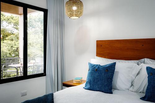 a bedroom with a bed with blue pillows and a window at Villas Santa Maria - Private Bay Lake Arenal in Nuevo Arenal