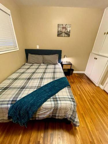 a bedroom with a bed with a plaid blanket on it at Entire Urban House Getaway Newly Remodeled in El Monte