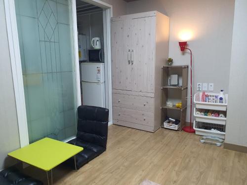 a living room with a yellow table and a chair at Daegu Little House in Daegu