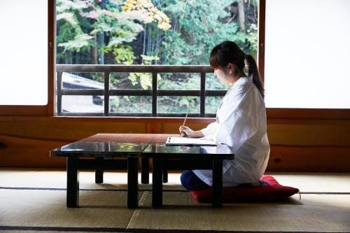 a girl sitting at a table writing on a laptop at Togakubo in Isehara