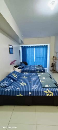 a bedroom with two beds and a blue curtain at SMDC Tagaytay Taal Lake Condo Cook Netflix No Balcony No Free Parking Contact to Confirm in Tagaytay