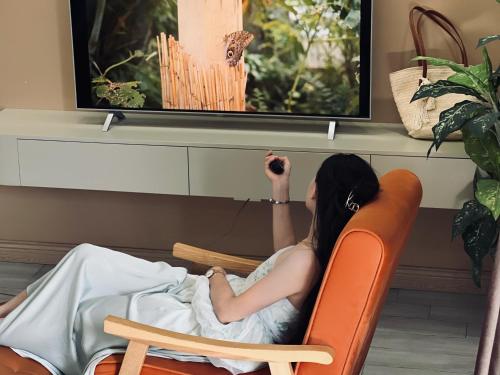 a woman sitting in a chair watching tv at Cat Ba Seoul 2 Hotel & Apartment in Cat Ba