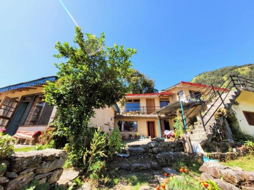 een huis met een boom ervoor bij Basanti Rawat Homestay in Munsyari