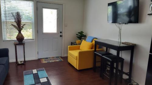 a living room with a yellow couch and a television at Guestsuite in wittier in Whittier