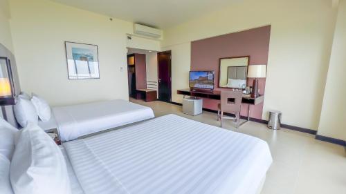 a hotel room with two beds and a television at Taal Vista Hotel in Tagaytay