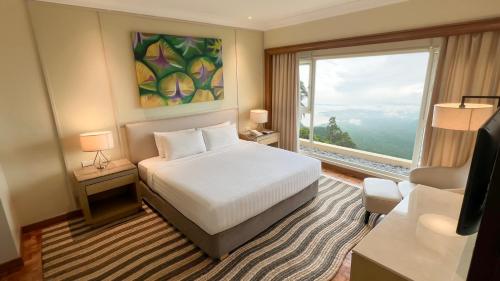 a hotel room with a bed and a large window at Taal Vista Hotel in Tagaytay