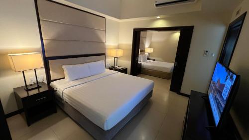 a bedroom with a white bed and a television at Taal Vista Hotel in Tagaytay