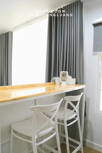 a desk with two white stools in front of a window at Cozy room in Khlongluang Ill - Self Check-in in Khlong Luang