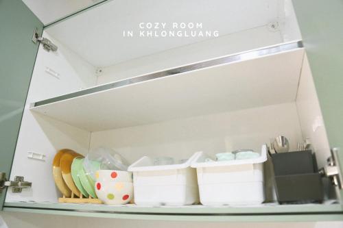 a shelf with cups and plates in a drawer at Cozy room in Khlongluang Ill - Self Check-in in Khlong Luang