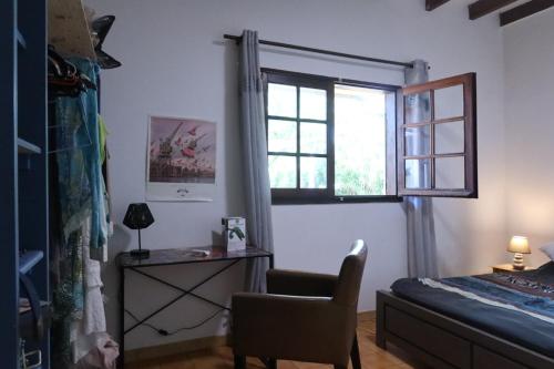 a bedroom with a bed and a chair and a window at Kaz a zot in Ravine des Cabris
