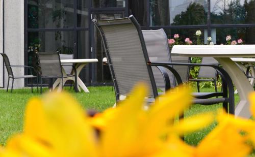a table and chairs in a yard with yellow flowers at La Saguenéenne - Hôtel et Centre de Congrès in Saguenay