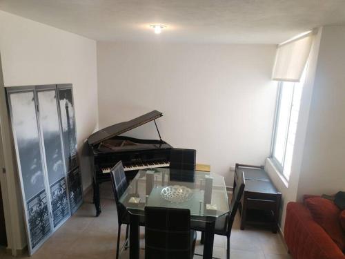 a dining room with a glass table and a piano at Departamento en pueblan puebla colonial in El Gallinero