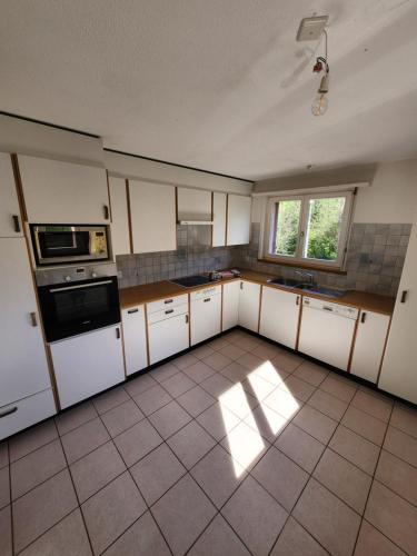 an empty kitchen with white cabinets and a window at La Villa Joly - Avenches in Avenches