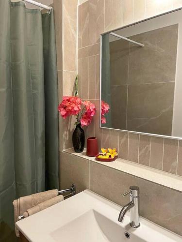 a bathroom with a sink and a mirror and pink flowers at Taapuna SunSet Moorea View in Atiue