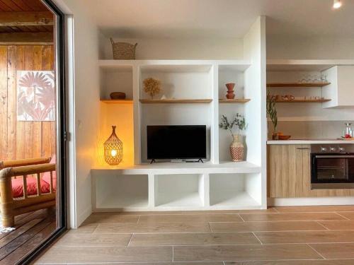 a living room with a tv on a white shelf at Taapuna SunSet Moorea View in Atiue