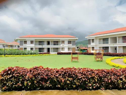two chairs on a lawn in front of a building at Mizzle Exotica Lonavala in Lonavala