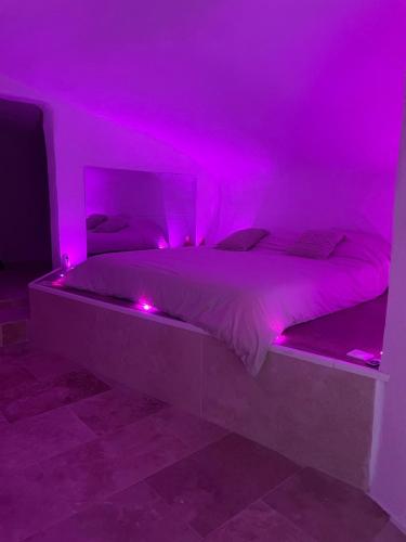 une chambre avec un lit avec des lumières roses dessus dans l'établissement Grotte love, à Pierrefeu-du-Var