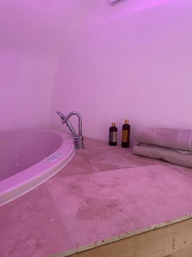 - une salle de bains pourpre avec une baignoire et 2 bouteilles de vin dans l'établissement Grotte love, à Pierrefeu-du-Var