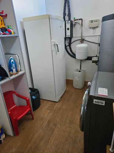 Cette chambre comprend un réfrigérateur et une chaise rouge. dans l'établissement Gîte Lo Becarut L'Escapade Des Flamants Roses, à Mireval