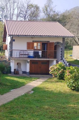 a small white house with a porch and a balcony at Kuća za odmor Denis in Mala Lešnica
